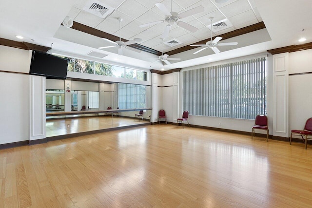 workout room featuring ornamental molding, light hardwood / wood-style floors, and a raised ceiling