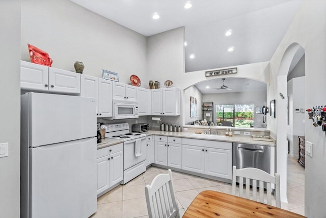 kitchen with a high ceiling, sink, white cabinets, and white appliances