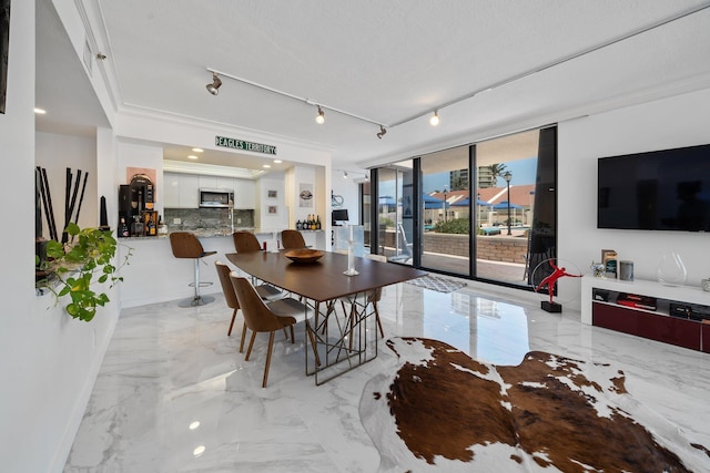 dining area featuring track lighting, floor to ceiling windows, and a textured ceiling