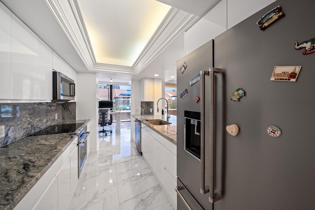 kitchen with sink, white cabinetry, crown molding, appliances with stainless steel finishes, and a raised ceiling