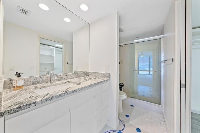 bathroom with tile patterned floors, vanity, toilet, and a shower with door