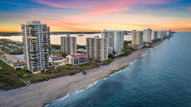 aerial view at dusk with a view of the beach and a water view