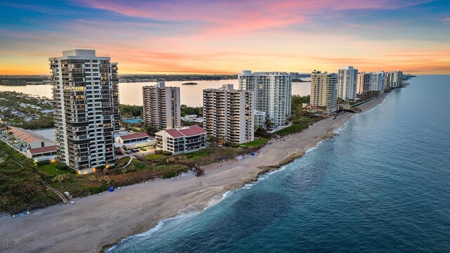 aerial view at dusk featuring a beach view and a water view