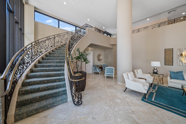 stairway featuring ornate columns, a towering ceiling, and tile patterned flooring