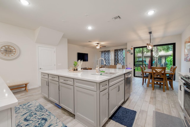 kitchen featuring sink, light hardwood / wood-style flooring, dishwasher, an island with sink, and pendant lighting