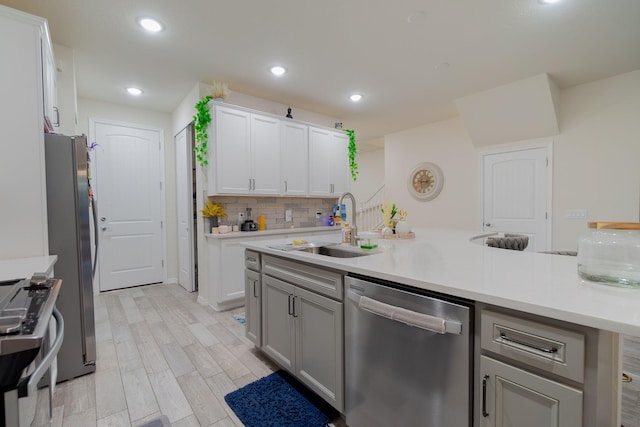 kitchen with stainless steel appliances, white cabinetry, sink, and light wood-type flooring