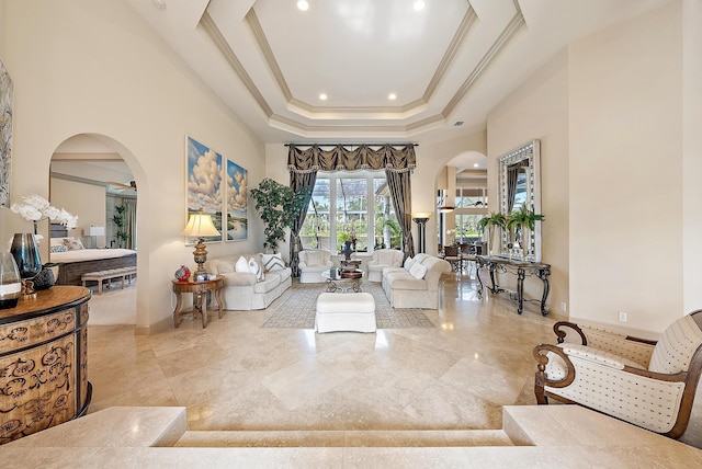 living room featuring a raised ceiling, ornamental molding, and a towering ceiling