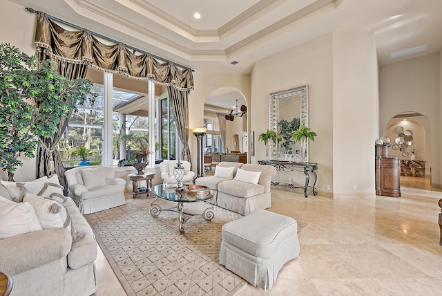 living room featuring ornamental molding, a towering ceiling, a chandelier, and a tray ceiling