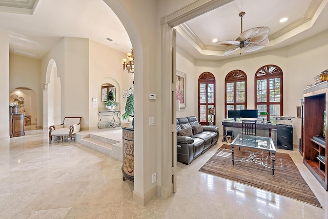 living room with a tray ceiling, ornamental molding, and ceiling fan