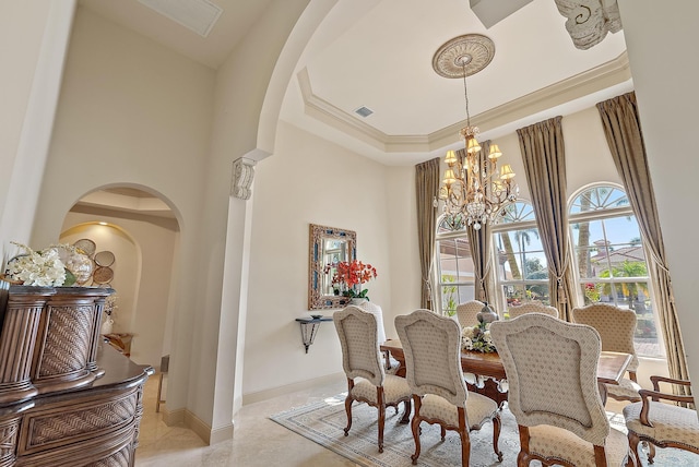 dining area with ornamental molding, a towering ceiling, an inviting chandelier, and a tray ceiling