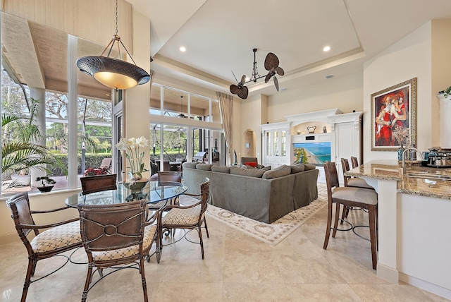 tiled dining area with sink, a raised ceiling, and a high ceiling