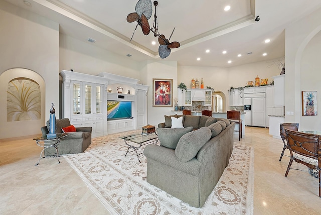 living room featuring a raised ceiling, crown molding, and a high ceiling