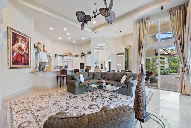 living room featuring a raised ceiling, crown molding, and a high ceiling