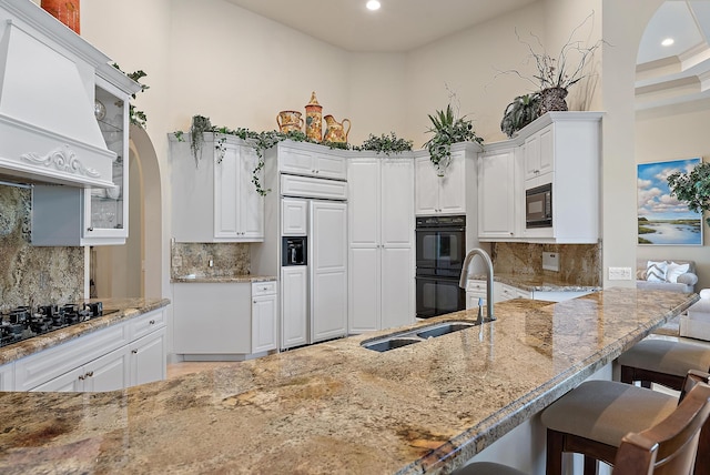 kitchen with black appliances, a breakfast bar, and white cabinets