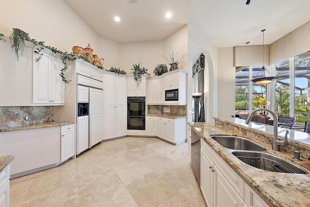 kitchen featuring sink, white cabinetry, hanging light fixtures, light stone countertops, and black appliances