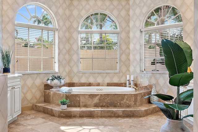 bathroom featuring vanity, a wealth of natural light, tiled bath, and tile walls