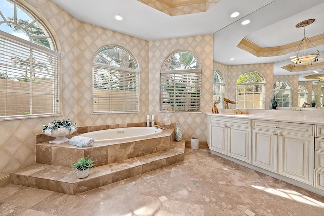 bathroom featuring tile walls, tiled bath, vanity, ornamental molding, and a tray ceiling