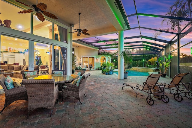 patio terrace at dusk featuring outdoor lounge area, ceiling fan, and a lanai