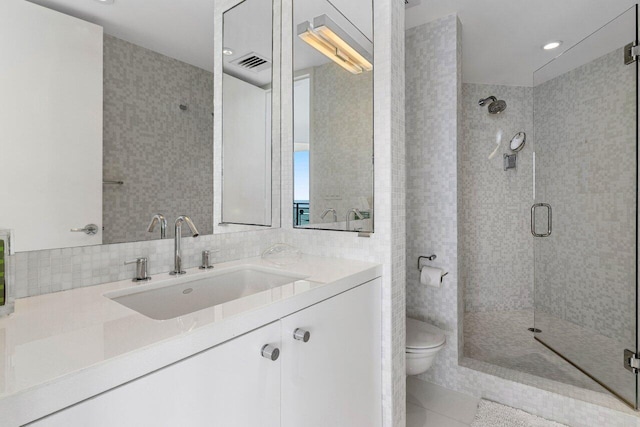 bathroom with tasteful backsplash, tile patterned flooring, vanity, walk in shower, and toilet