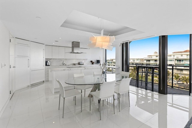 dining room with floor to ceiling windows, a raised ceiling, and sink