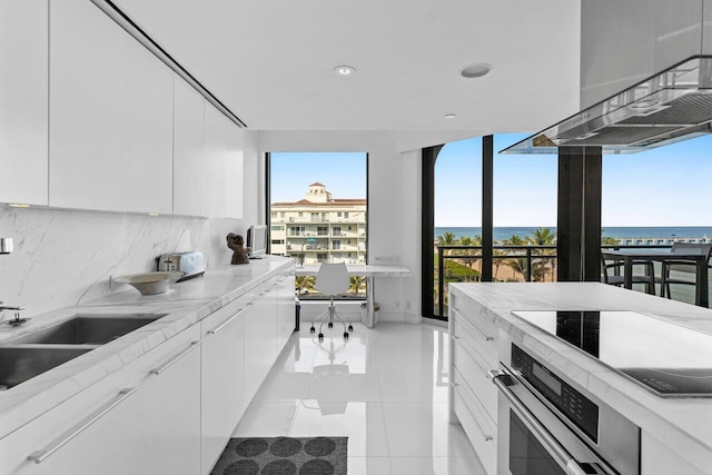 kitchen with white cabinetry, backsplash, and stainless steel oven