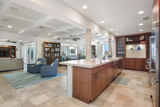 kitchen featuring high end refrigerator, beamed ceiling, ceiling fan, and a kitchen island with sink