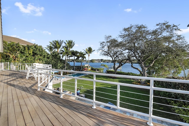 wooden terrace with a water view and a yard