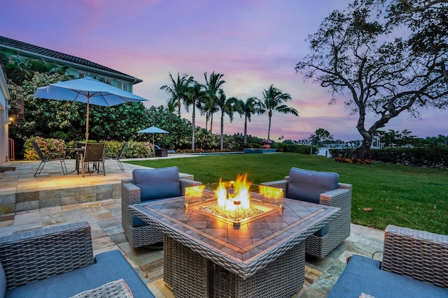 patio terrace at dusk with a fire pit and a yard