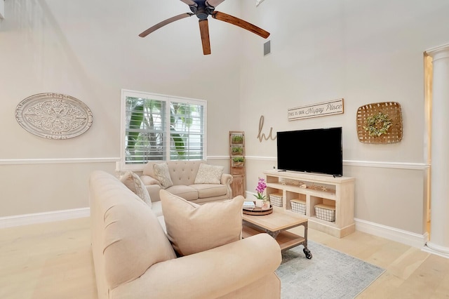 living room with light hardwood / wood-style floors, a towering ceiling, and ceiling fan