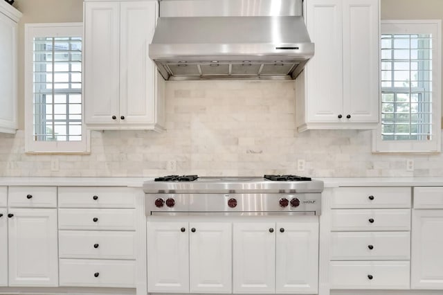 kitchen featuring stainless steel gas stovetop, white cabinets, wall chimney exhaust hood, and tasteful backsplash