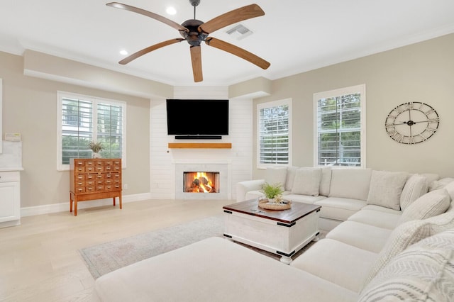 living room with a fireplace, light hardwood / wood-style flooring, ceiling fan, and a healthy amount of sunlight