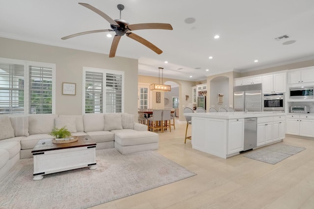 living room featuring ceiling fan, sink, and ornamental molding