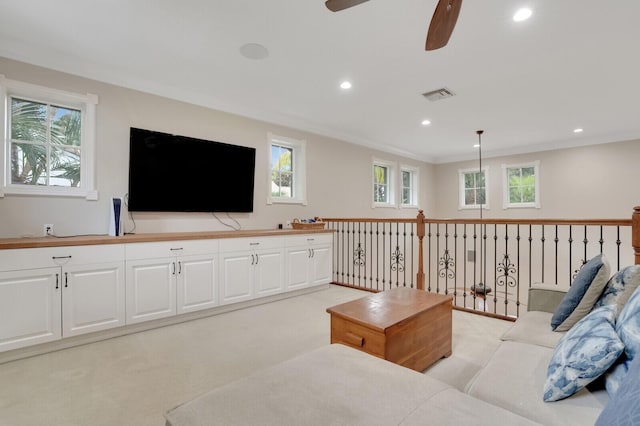 living room featuring ceiling fan, ornamental molding, and light carpet