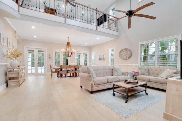 living room featuring light hardwood / wood-style floors, a high ceiling, french doors, and ceiling fan with notable chandelier