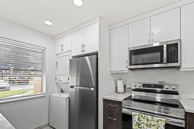 kitchen with white cabinets, stainless steel appliances, dark brown cabinetry, and stacked washer and clothes dryer