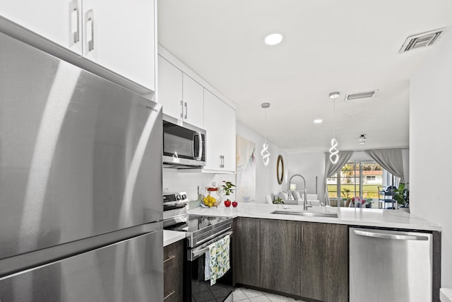 kitchen with pendant lighting, sink, appliances with stainless steel finishes, white cabinetry, and dark brown cabinetry