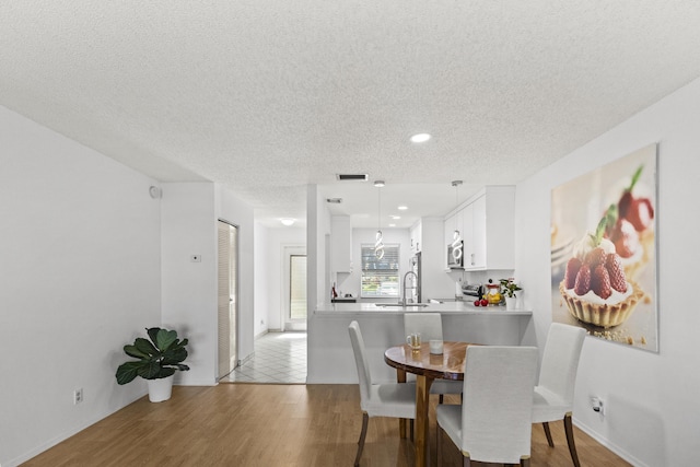 dining room featuring sink, hardwood / wood-style floors, and a textured ceiling