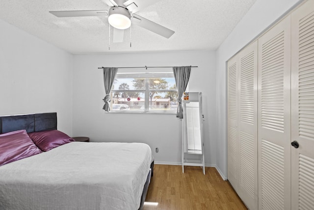 bedroom featuring a textured ceiling, wood-type flooring, a closet, and ceiling fan