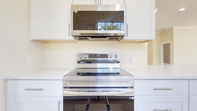 kitchen with stainless steel appliances, white cabinetry, crown molding, and light stone counters