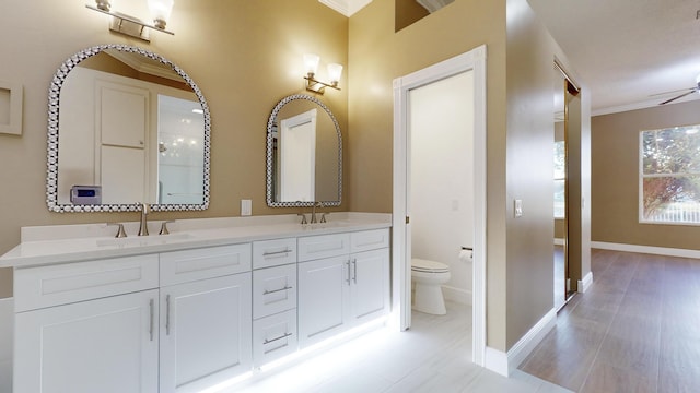 bathroom with ornamental molding, vanity, and toilet