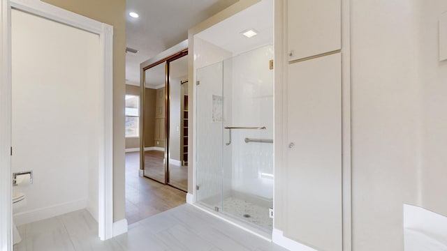 bathroom featuring a shower with door and toilet