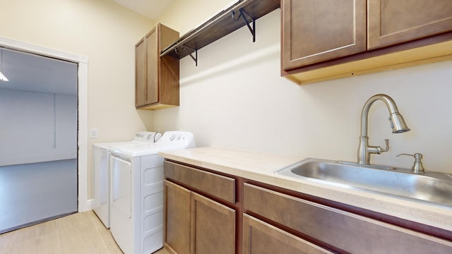 clothes washing area featuring sink, cabinets, and washing machine and clothes dryer