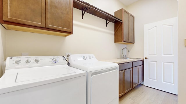 washroom with separate washer and dryer, sink, light hardwood / wood-style floors, and cabinets