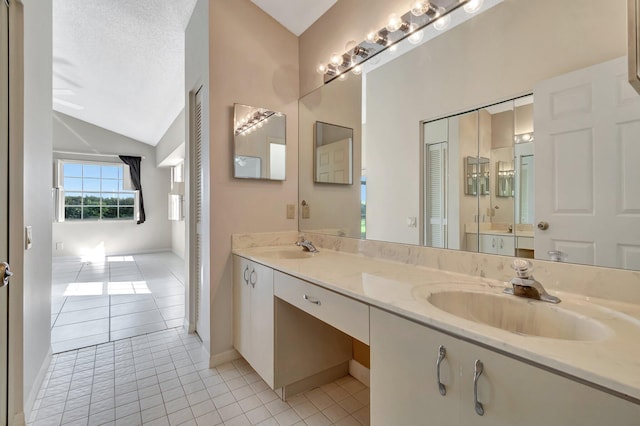 bathroom featuring lofted ceiling, vanity, tile patterned floors, and a textured ceiling