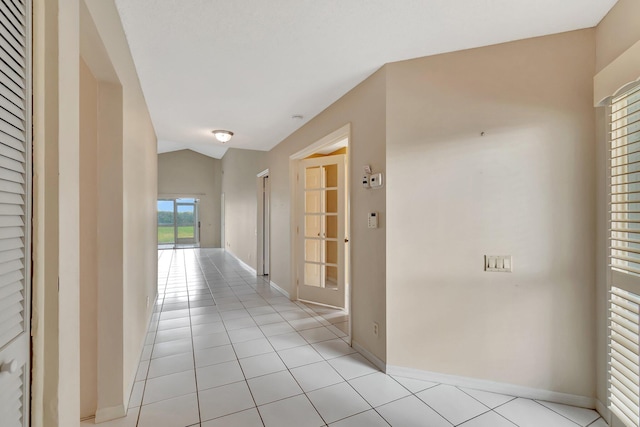 hallway with lofted ceiling and light tile patterned floors