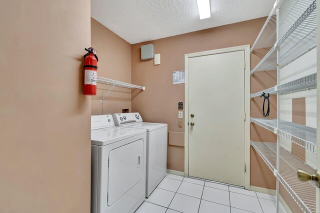 laundry area featuring separate washer and dryer, light tile patterned floors, and a textured ceiling