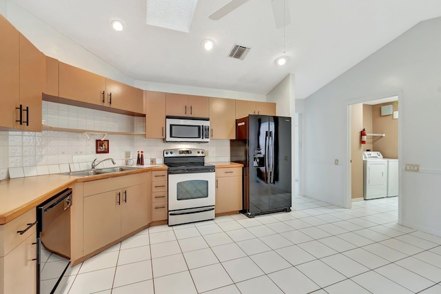 kitchen featuring sink, backsplash, vaulted ceiling with skylight, black appliances, and light brown cabinetry