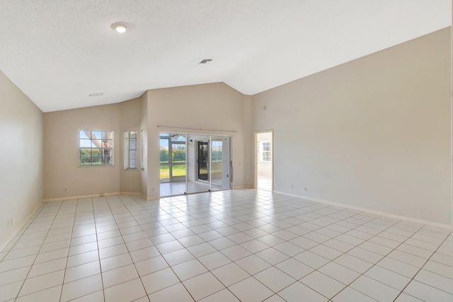 empty room featuring high vaulted ceiling, a textured ceiling, and light tile patterned floors