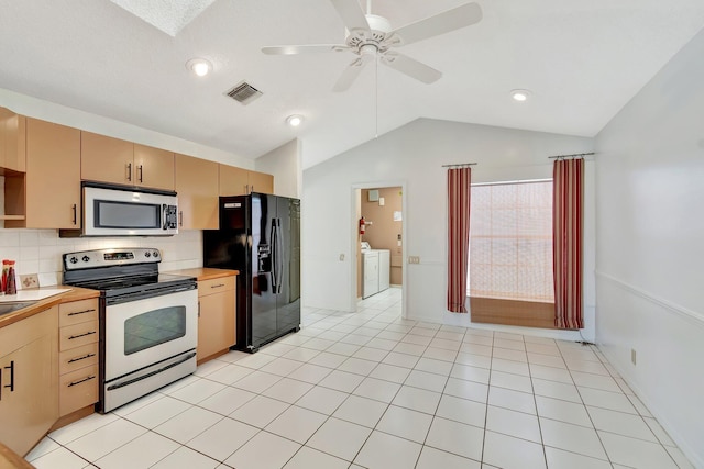 kitchen featuring washing machine and clothes dryer, lofted ceiling, light brown cabinets, stainless steel appliances, and backsplash