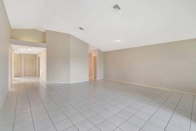 spare room with light tile patterned flooring and lofted ceiling